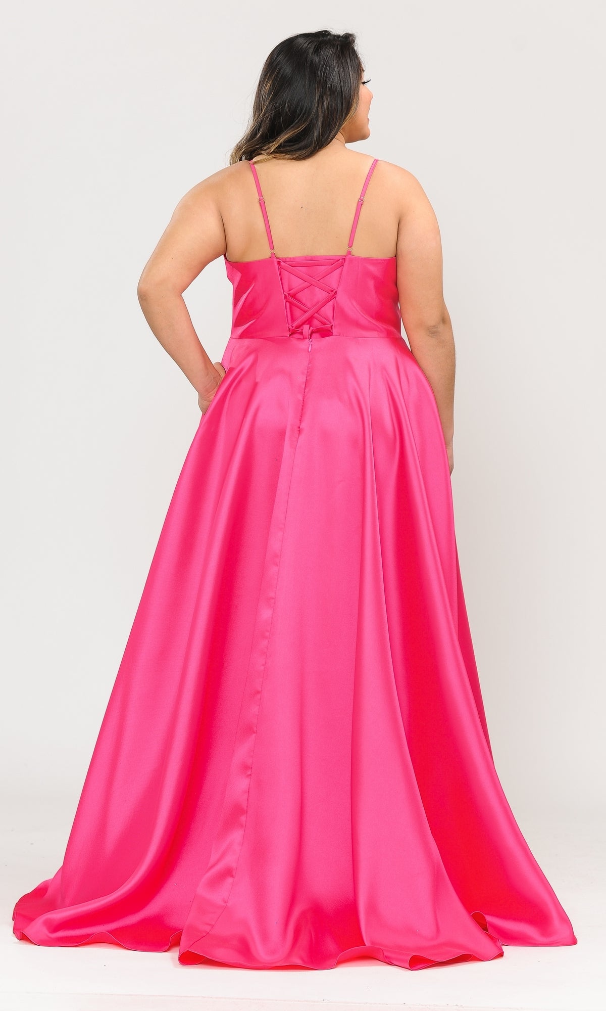 A woman faces away, modeling the Plus-Size Long Corset Prom Dress with Pockets W1070 in bright pink satin, featuring thin straps and a lace-up back.